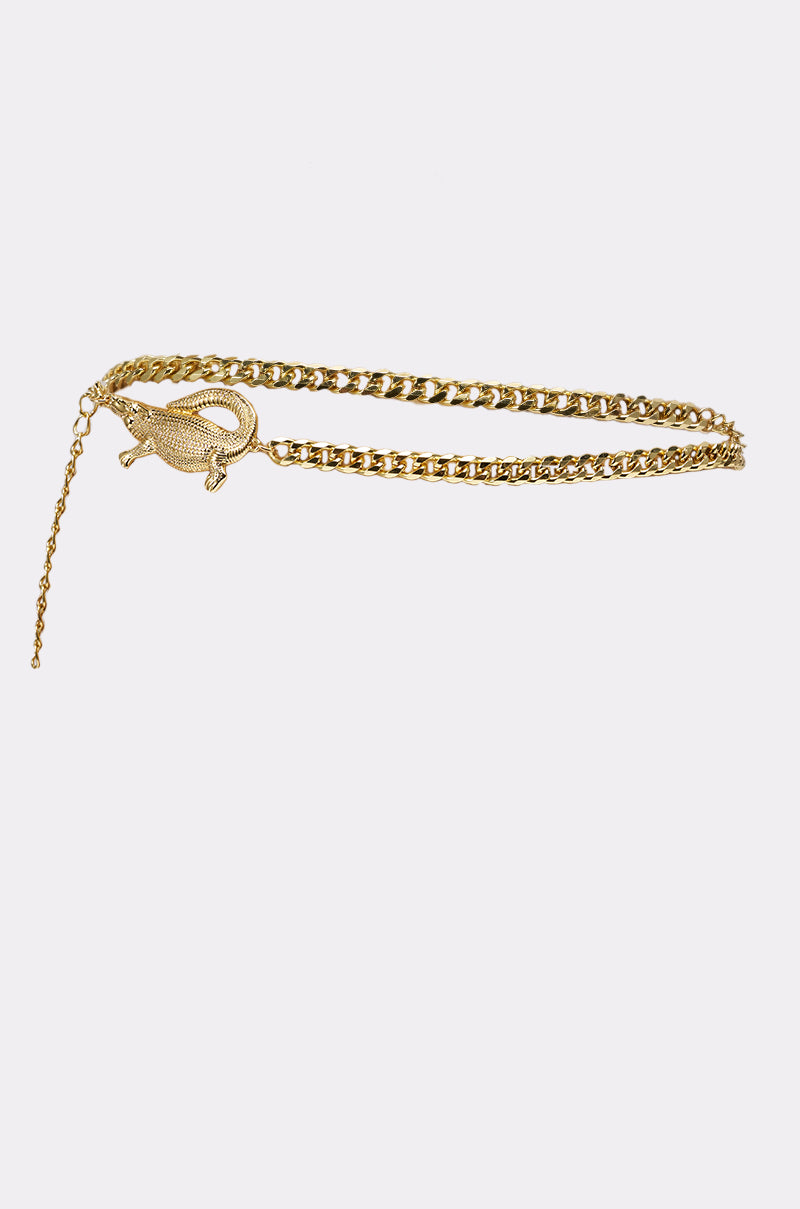 The BITE ME CHAIN BELT is a bold gold chain accessory with a detailed crocodile buckle, shown against a plain white background. 2