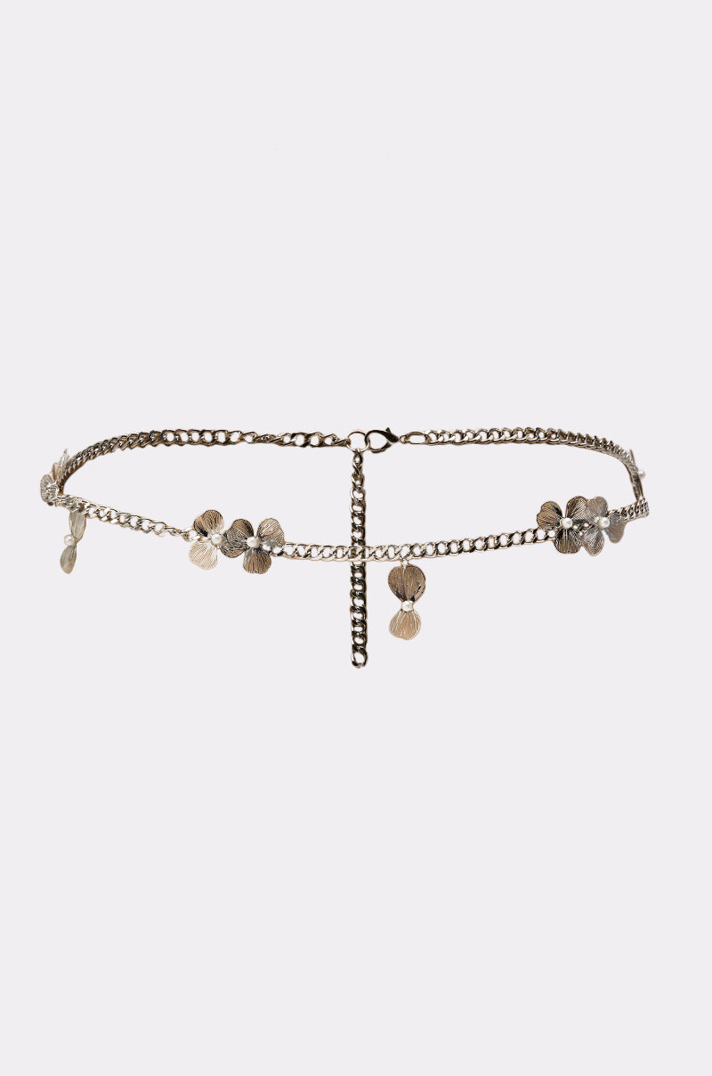 The FLORAL BITS CHAIN BELT is a delicate silver chain belt with flower-shaped charms and an adjustable dangling chain, shown against a plain white background. 1