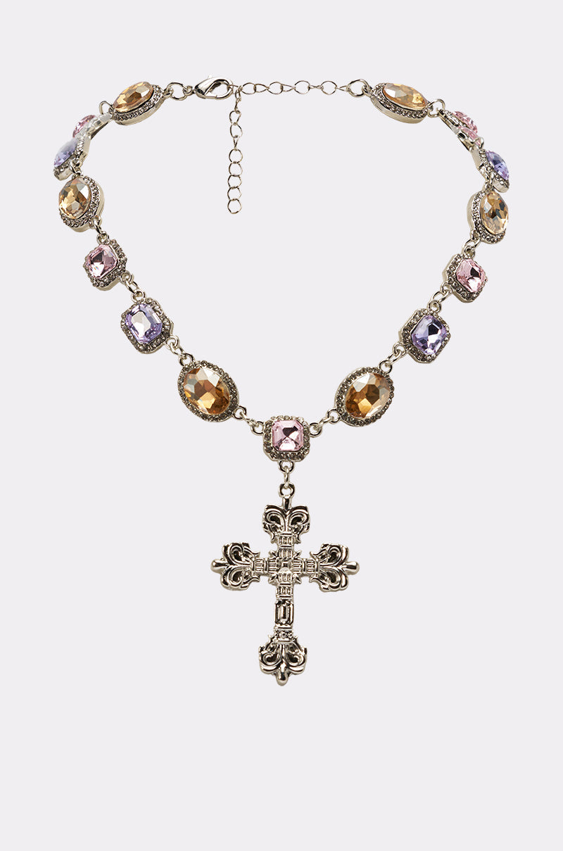 The MY LEGACY NECKLACE is a vintage-inspired multicolor statement piece with oval and rectangular gold, pink, and purple gemstones, centered by an ornate crystal cross pendant. An adjustable chain clasp provides the perfect fit. 0