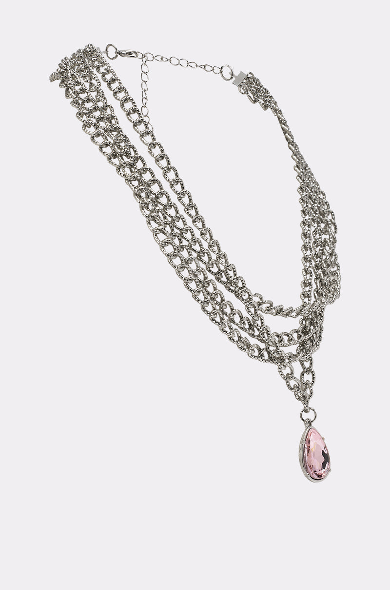 The PRINCESS TREATMENT NECKLACE is a layered multi-chain silver necklace with a bold, oval light pink pendant on the longest chain, making a striking crystal statement. 2
