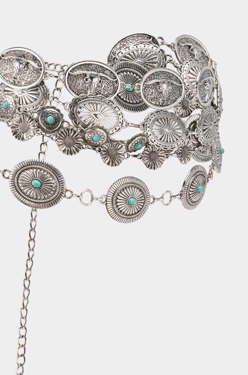 The WILD WEST LAYERED CHAIN BELT features round, engraved silver conchos with floral designs and turquoise stones, linked by rings and layered chains, displayed on a light gray background. 4