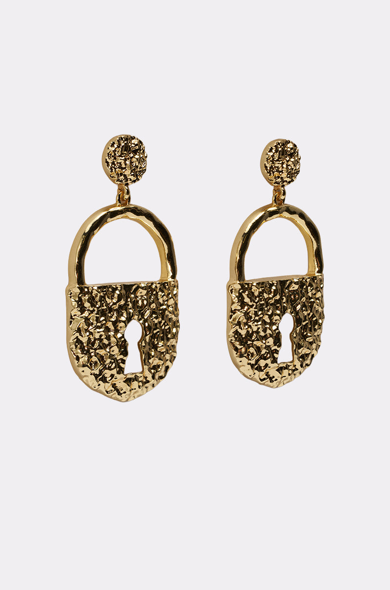 The ON LOCK EARRING features chunky gold-tone padlock drops with keyhole cutouts and a hammered texture, suspended from round textured studs, set against a plain light background. 2