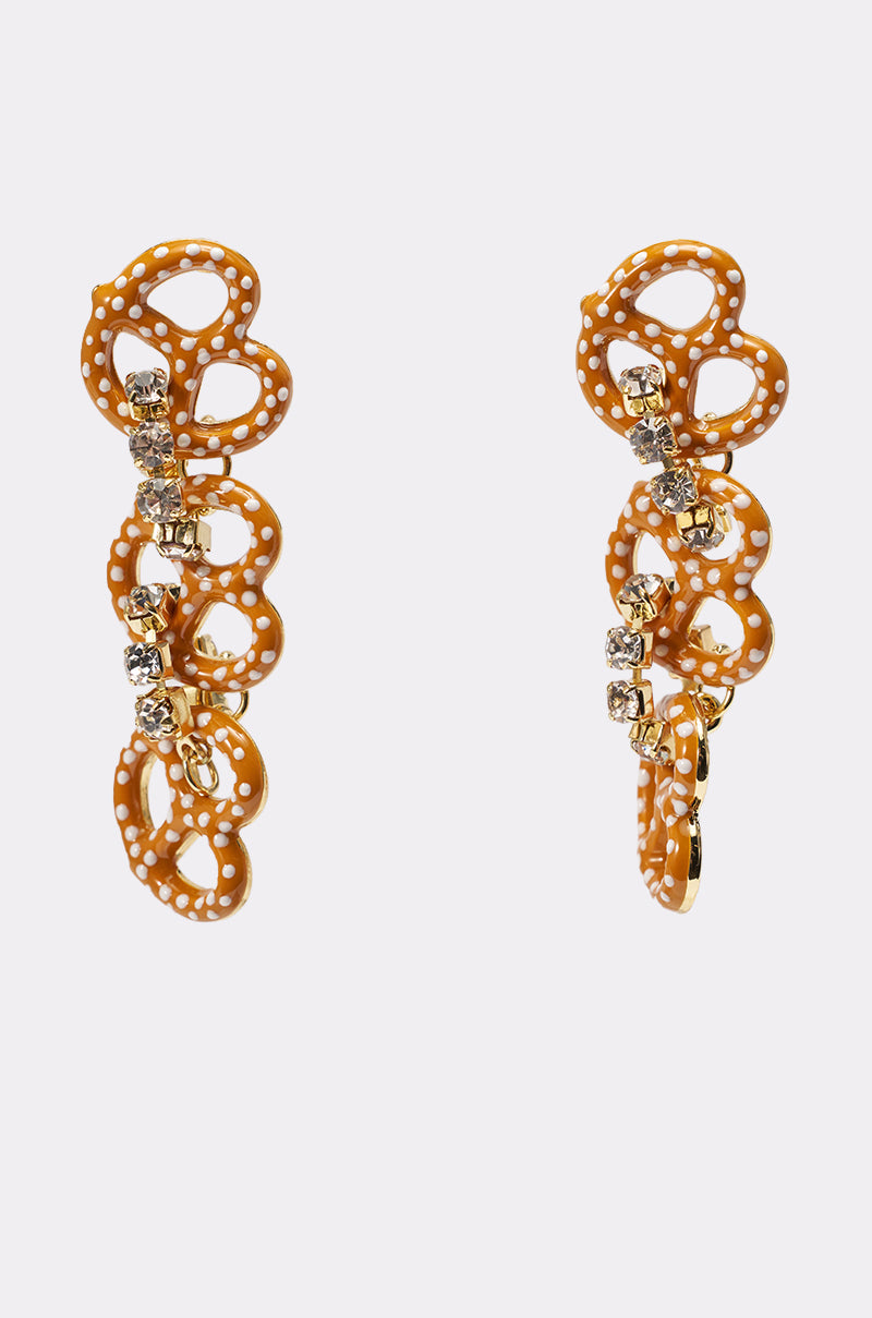 The NEVER SALTY EARRING features gold-tone pretzel drops adorned with small white dots and vertical rows of clear sparkling stones, making them the perfect statement earrings against a plain white background. 1
