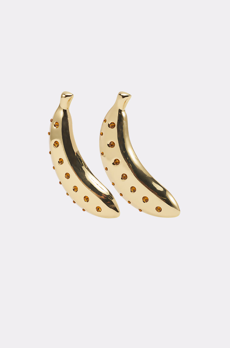 The GOING BANANAS EARRING set features two gold-tone statement banana earrings embellished with small amber rhinestones, showcased on a simple light gray background. 2