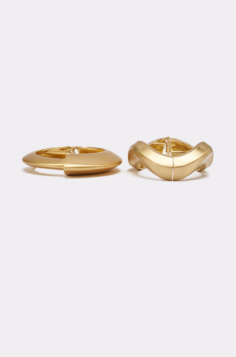 The ULTIMATE STACK BRACELET SET is displayed side by side on a light grey background—one piece smooth and rounded, the other sculpted with a wavy design—both ideal for pairing with your favorite chunky gold jewelry. 3
