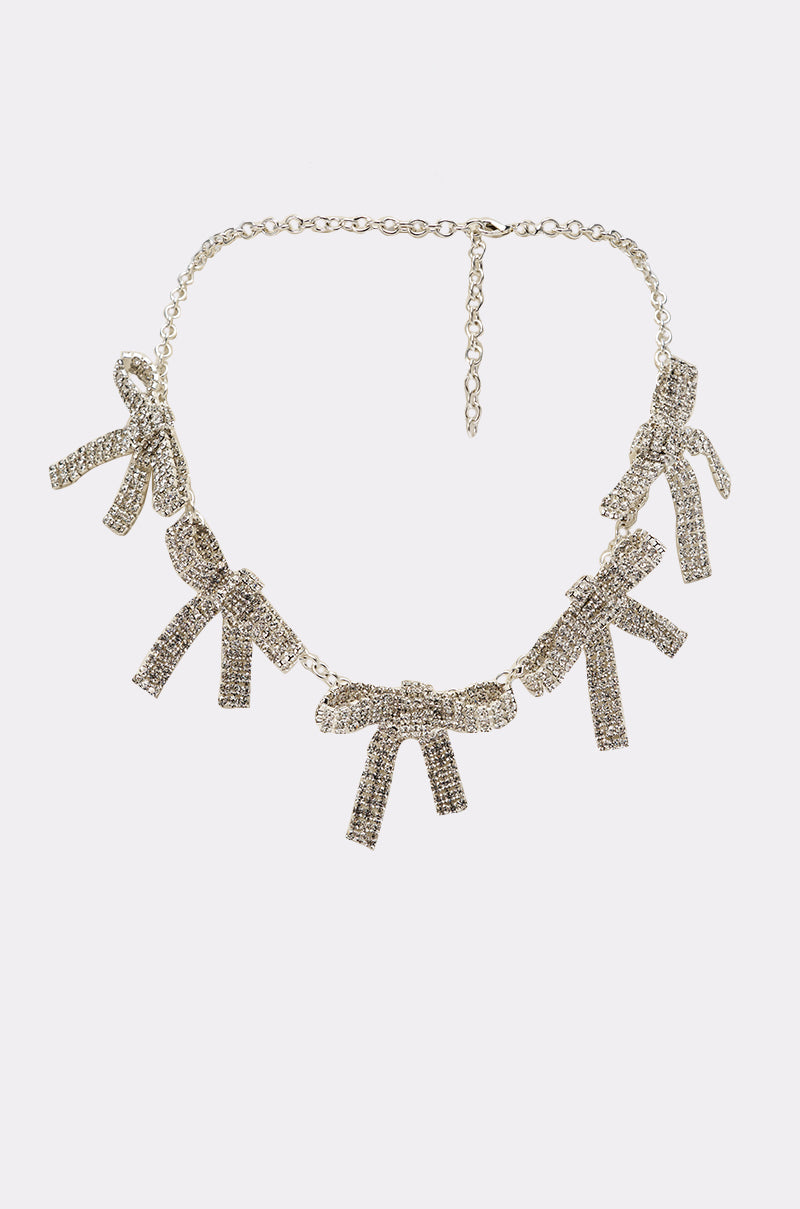 The IM THE GIFT NECKLACE features a gold chain with five sparkling, crystal-encrusted bow charms, evenly spaced for a coquette-inspired look. Shown on a plain white background. 1