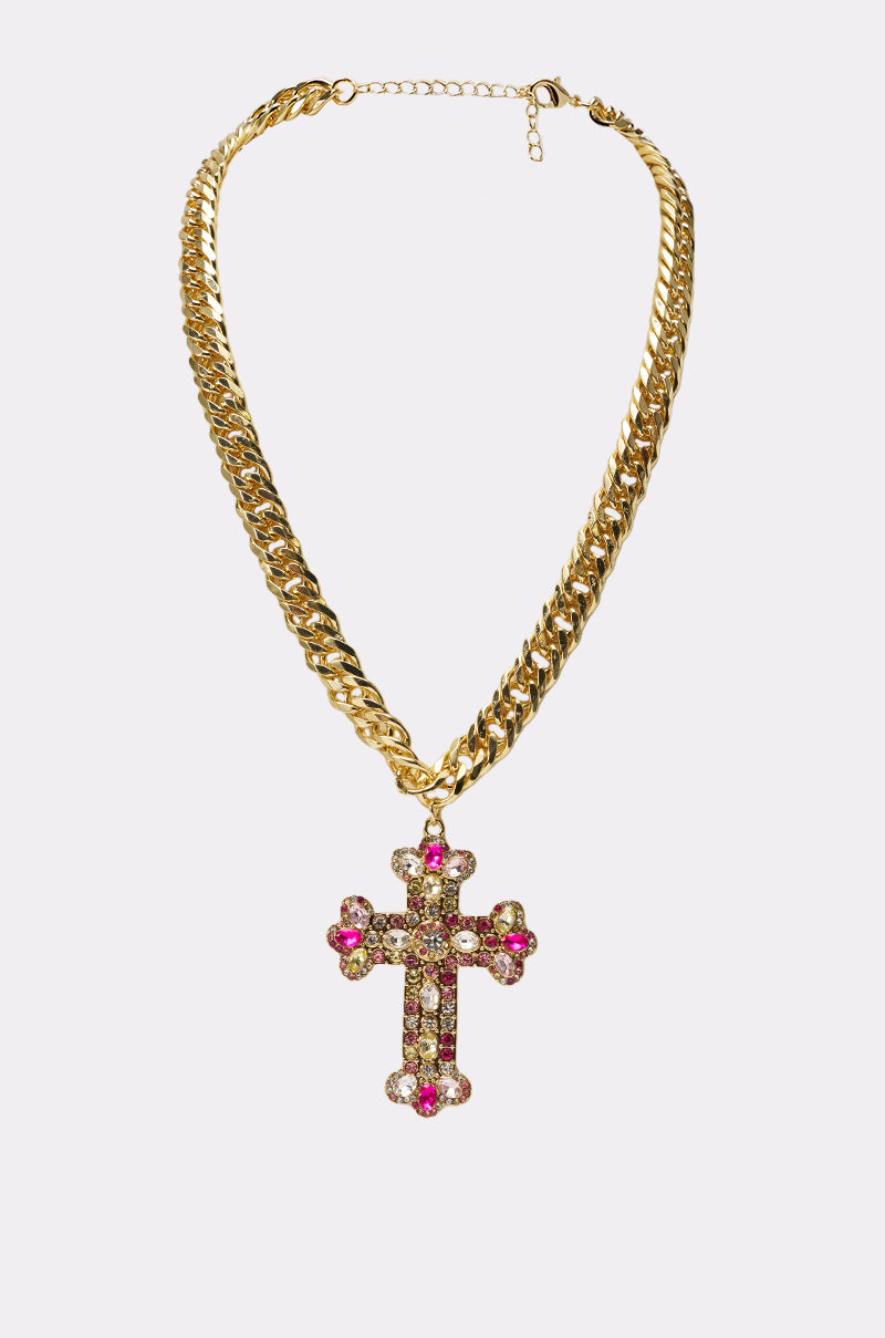 The PERRY NECKLACE is a gold Cuban-link chain featuring a large cross pendant adorned with sparkling pink and clear gemstones and multicolor rhinestones, creating an intricate, colorful design on a white background. 0