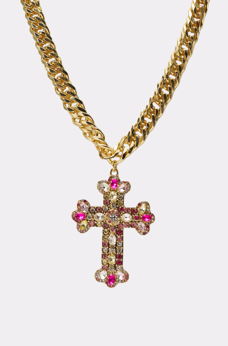 The PERRY NECKLACE is a gold Cuban link chain with a cross-shaped pendant, embellished with pink and clear rhinestones, shown on a plain white background. 2