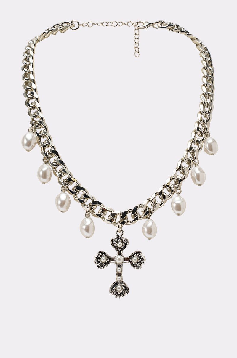The TRINA NECKLACE is a silver Cuban-link chain featuring hanging faux pearls and a large ornate cross pendant embellished with pearls and small gemstones. 0