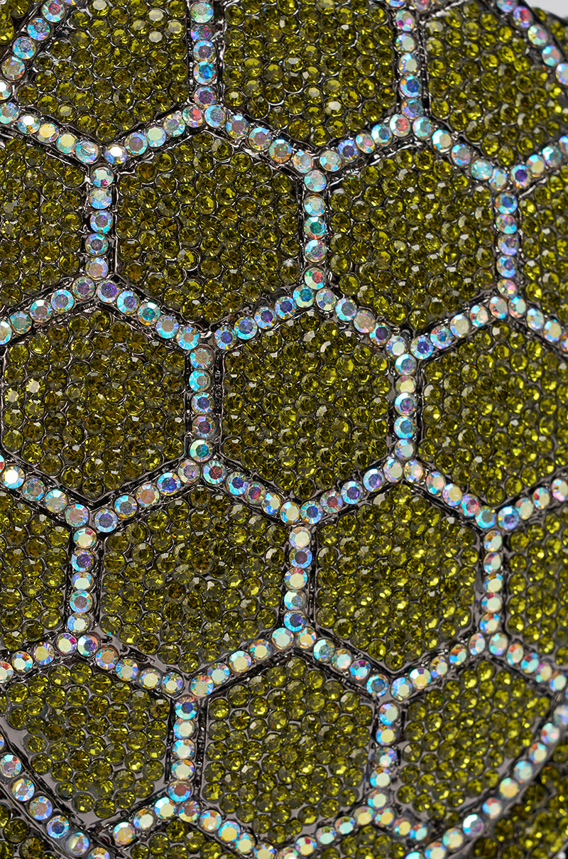 A close-up of the BY THE SEA BLING PURSE showcases its textured surface with hexagonal patterns outlined in iridescent crystals and filled with sparkling green gems, resembling a statement evening bag. 5
