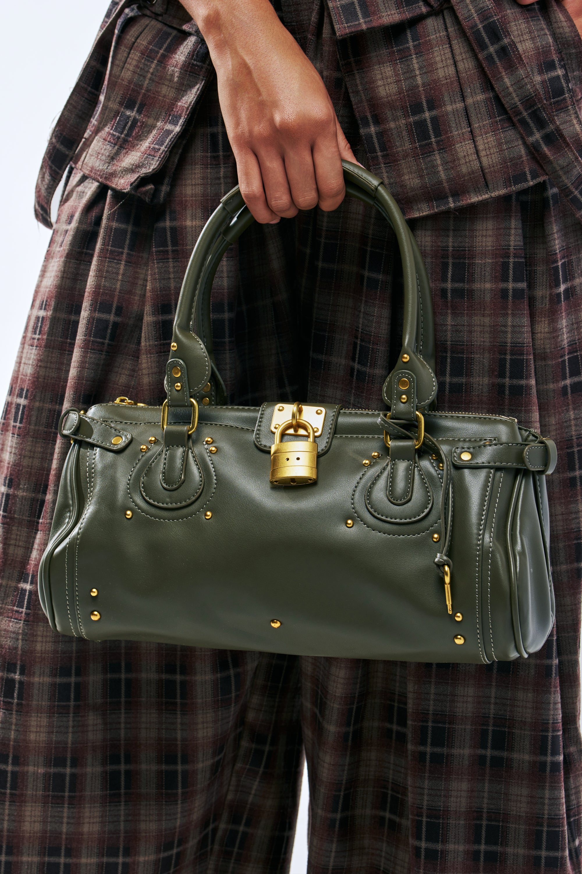 LOVE LOCKDOWN PURSE, an olive green faux leather handbag featuring gold studs, a central padlock closure, and top handles.