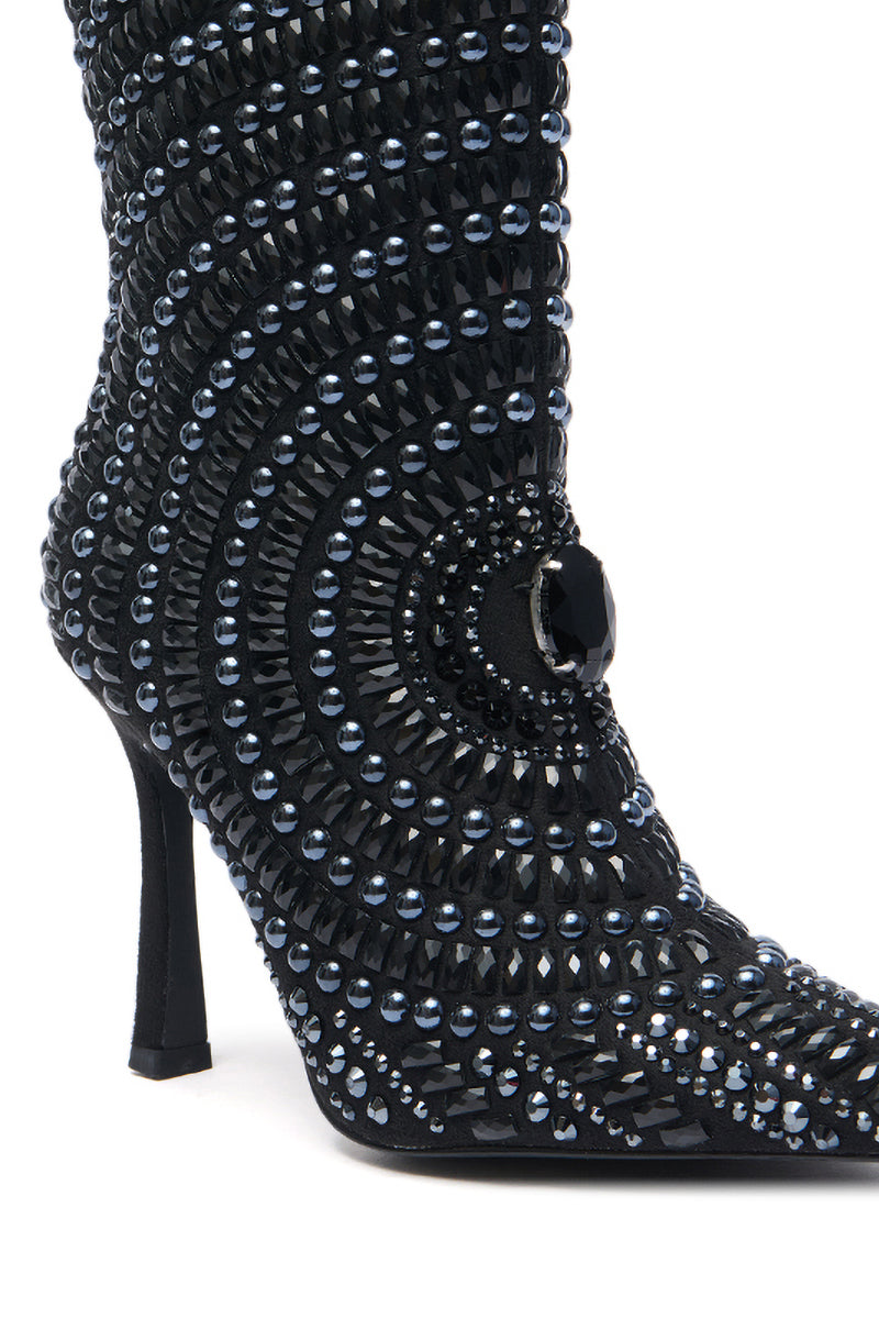 The AZALEA WANG HILLEL PEWTER RHINESTONE BOOTIE is a black faux suede stiletto boot adorned with rows of black and silver studs and a large black gem accent near the ankle.