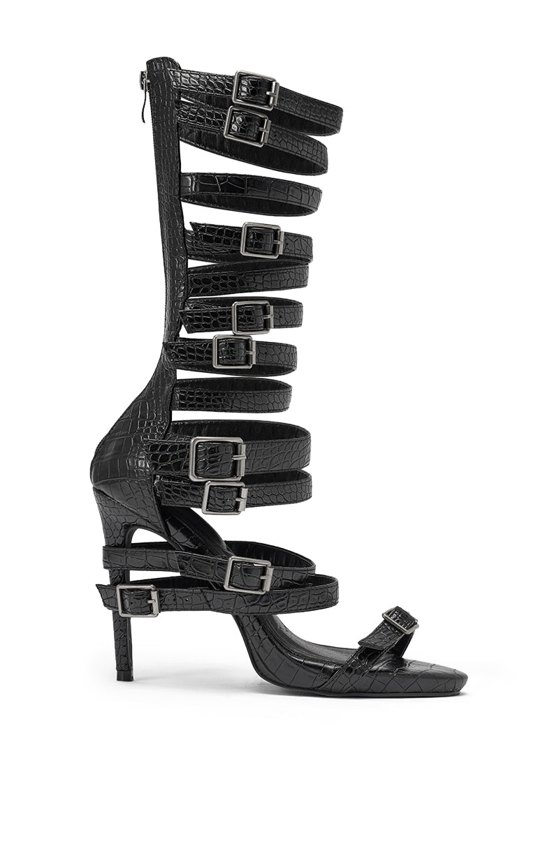 The AZALEA WANG HITCH BLACK CROC HARDWARE EMBELLISHED STILETTO SANDAL is a tall, black faux leather gladiator-style sandal with croc-embossed texture, stiletto heels, and multiple silver buckled straps running up the leg. 3