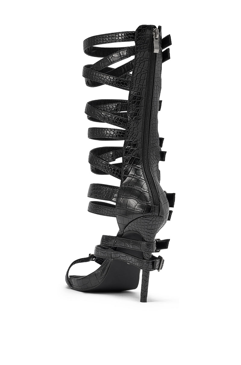 The AZALEA WANG HITCH BLACK CROC HARDWARE EMBELLISHED STILETTO SANDAL features croc-embossed faux leather, a statement heel, multiple horizontal textured straps, and a back zipper, shown side-on against a white background. 5