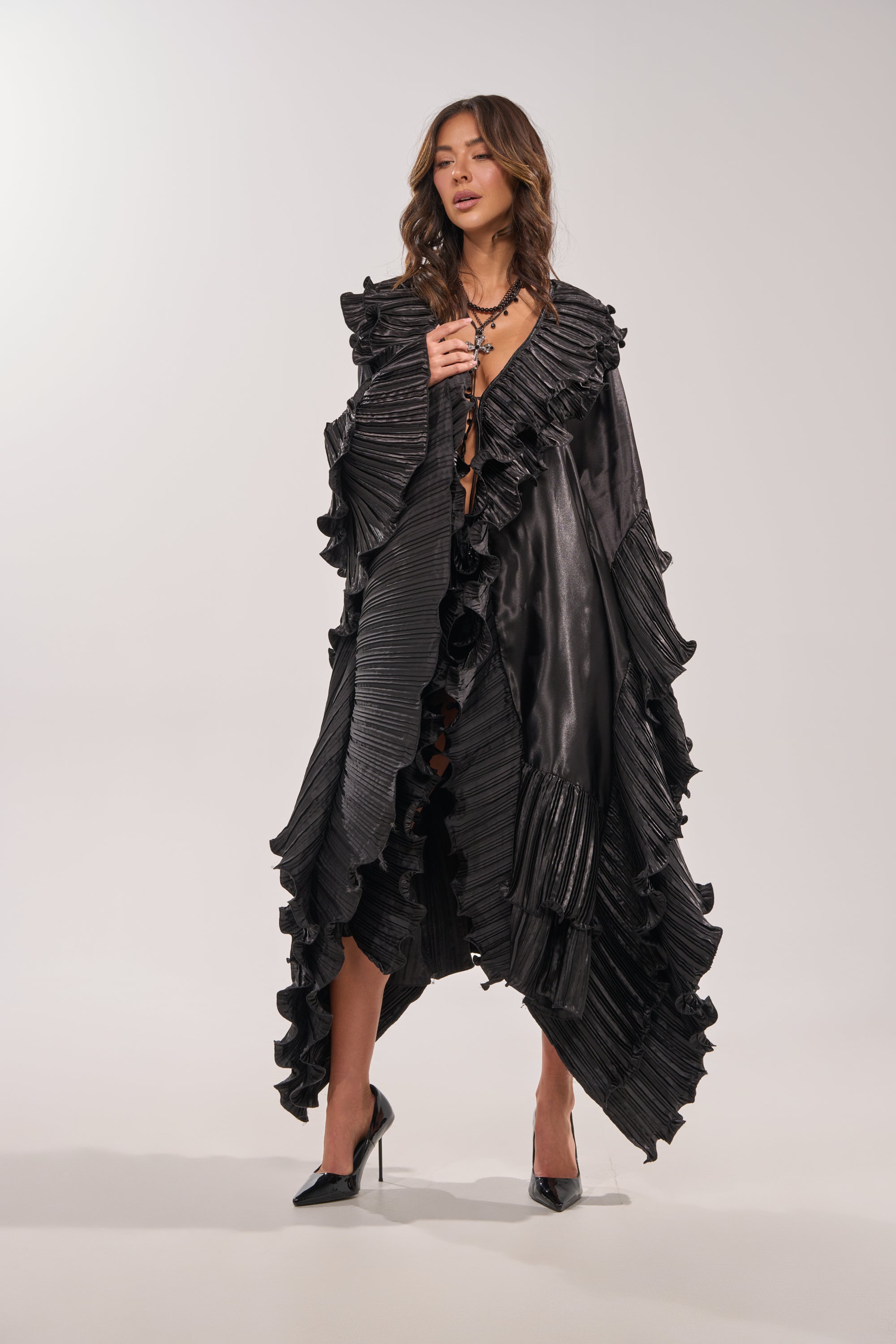 A woman models the SHINE ON LONG SLEEVE FRONT TIE TOP with layered necklaces and black high heels, standing against a plain light background. 5