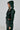 Clad in an evergreen MONTE CARLO HOODED MOTO faux leather jacket and matching skirt, a person looks sideways. The outfit features silver buckles and a belted waist against a light background.
