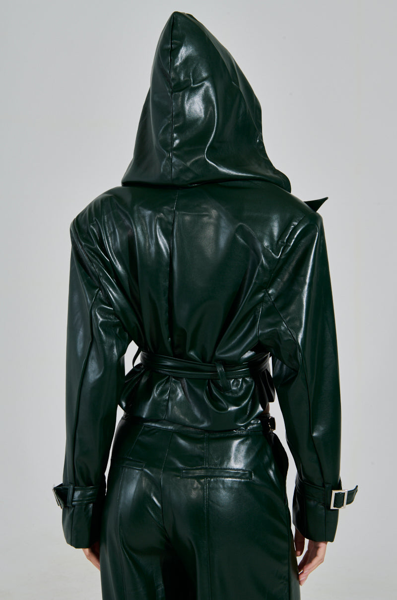 The MONTE CARLO HOODED MOTO in evergreen shows a back view of a person with the faux leather hood up, matching pants, buckled cuffs, and a belted waist against a gray background.