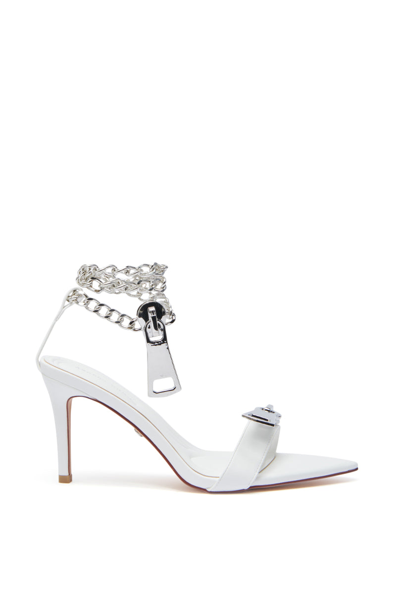 The AZALEA WANG HORUS WHITE ZIPPER EMBELLISHMENT SANDAL features a white faux leather pointed toe, thin stiletto heel, metallic front strap, and an ankle strap with silver chain links and a zipper pull accent.
