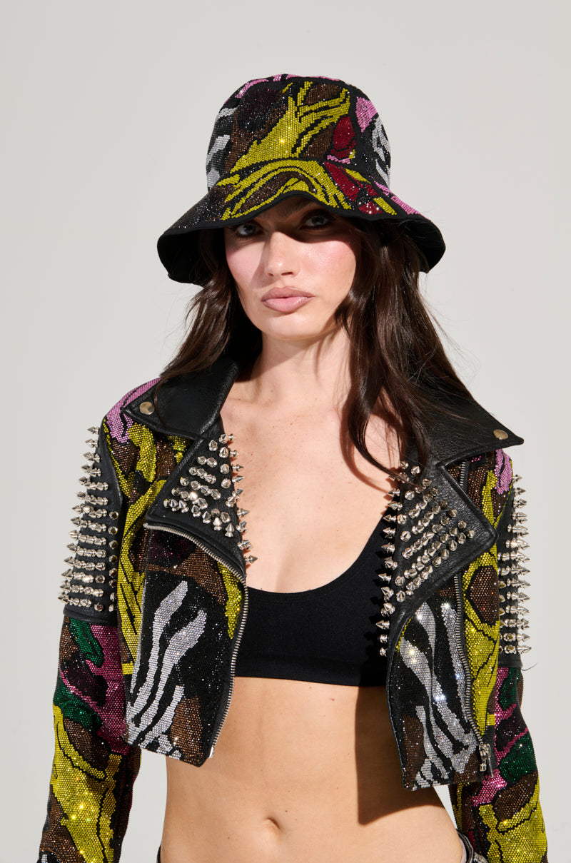A person wearing the TOO HOT BLING BUCKET HAT and a sequined jacket with zebra patterns and spiked studs dazzles against the plain, light gray background. Under the jacket, a black top adds contrast to this bold fashion accessory statement.
