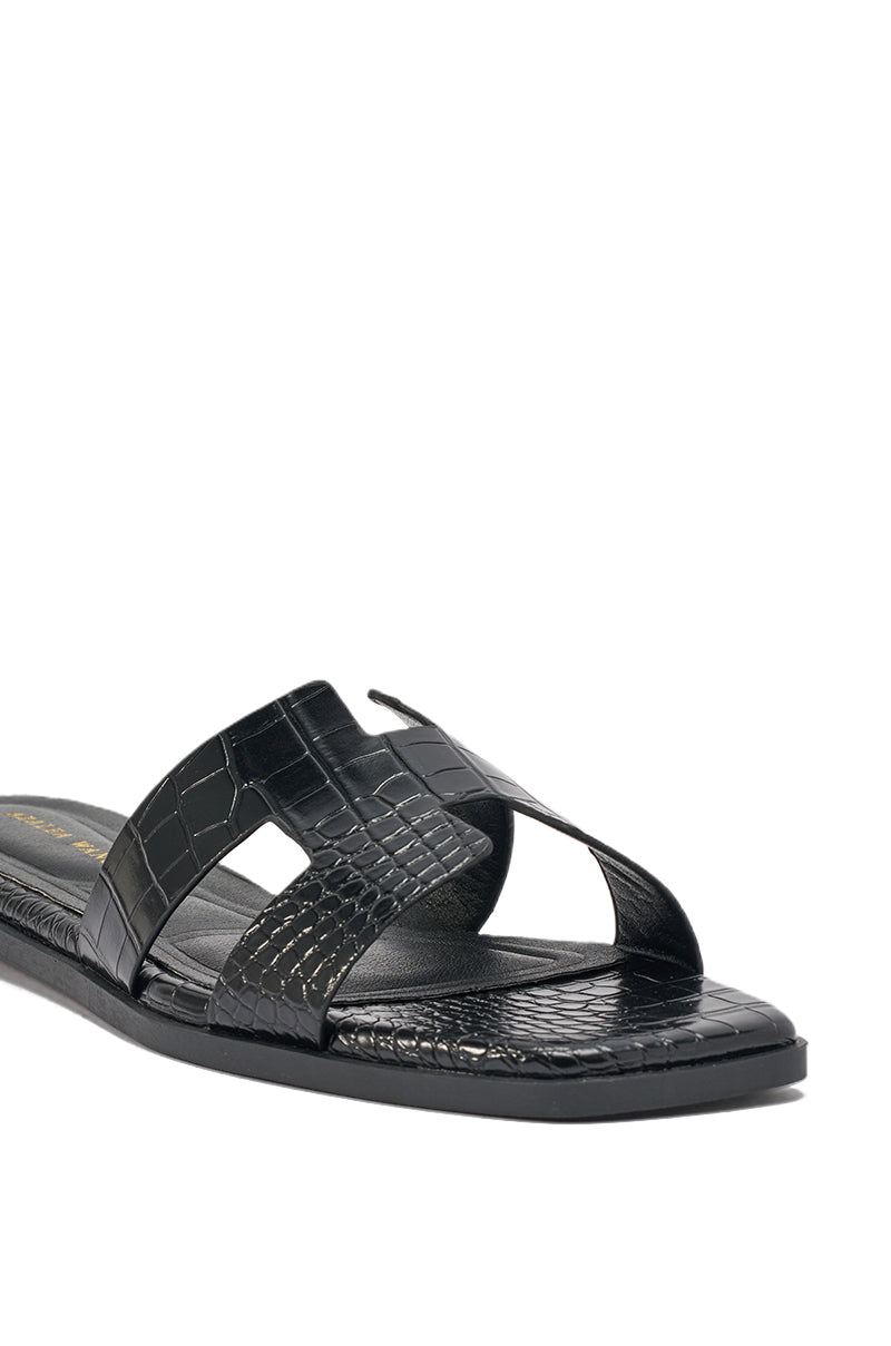 The AKIRA HOWDY BLACK CROC SLIP ON FLAT SANDAL, featuring wide crisscross crocodile-embossed faux leather straps and a square toe, is displayed against a white background. 7