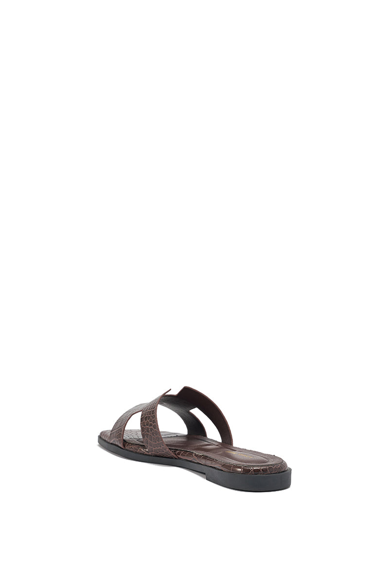 The AKIRA HOWDY BROWN CROC SLIP ON FLAT SANDAL features a crisscross crocodile-embossed faux leather strap and a flat black sole, shown from the back at an angle on a white background. 8