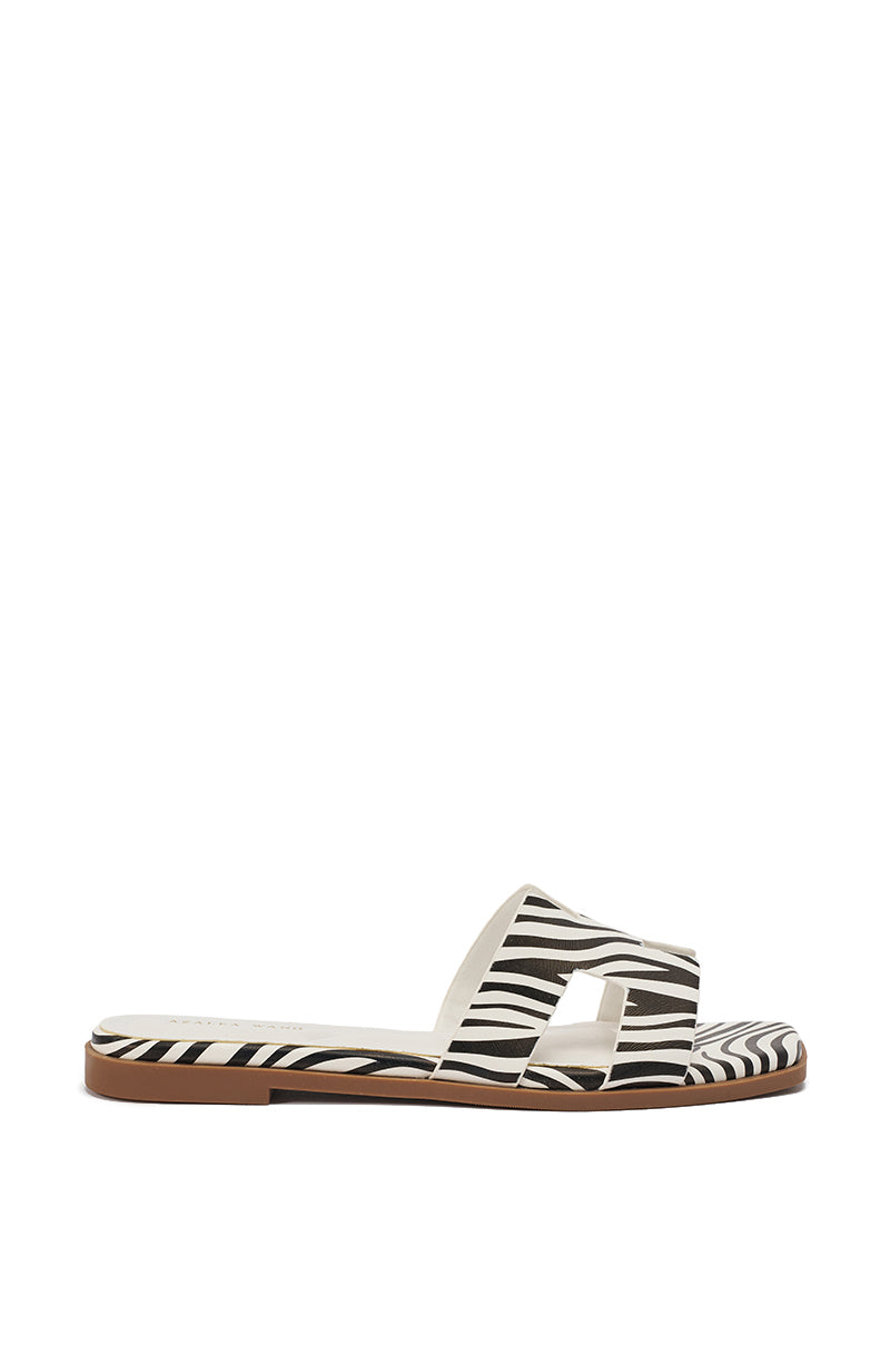 The AKIRA HOWDY ZEBRA SLIP ON FLAT SANDAL features a zebra-print design, a wide H-shaped strap, an open toe, and a low brown sole with a comfort cushion insole for all-day wear. 4