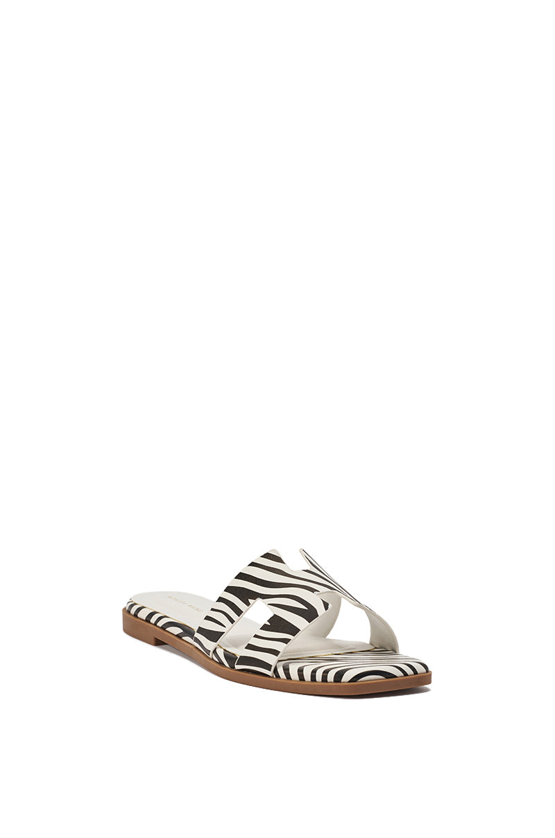 The AKIRA HOWDY ZEBRA SLIP ON FLAT SANDAL features black and white zebra-print straps, an open toe, cushioned insole, and a brown sole, shown on a white background. 5