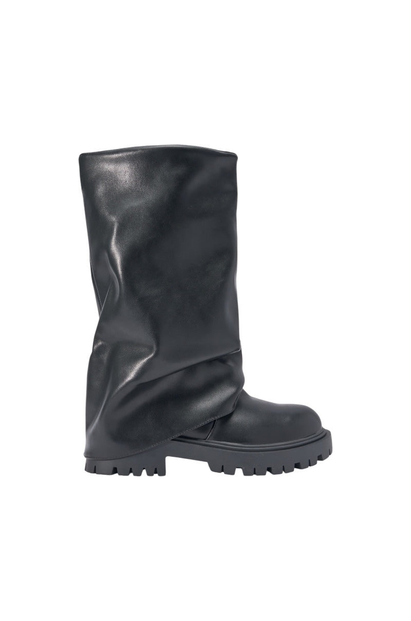 The AZALEA WANG HOYT BLACK FLAT RUCHED BOOTIE features a slouchy, knee-high design with chunky platform lug sole and a wrinkled faux leather look, shown from the side against a white background. 3