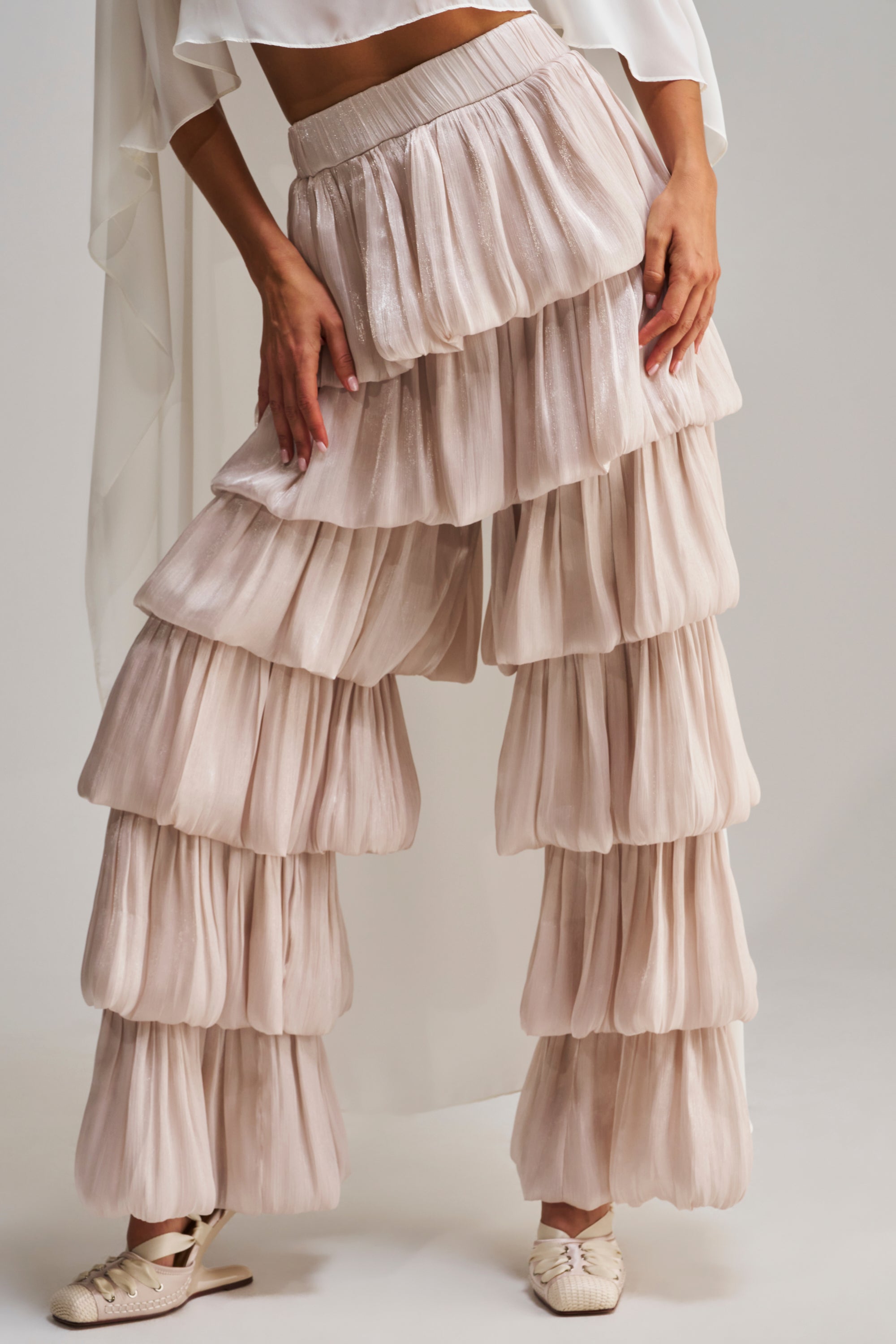 Wearing the STAR OF THE NIGHT FLOUNCY PANT IN IVORY, styled with a matching top, this look features voluminous pleated layers and is paired with light woven shoes.