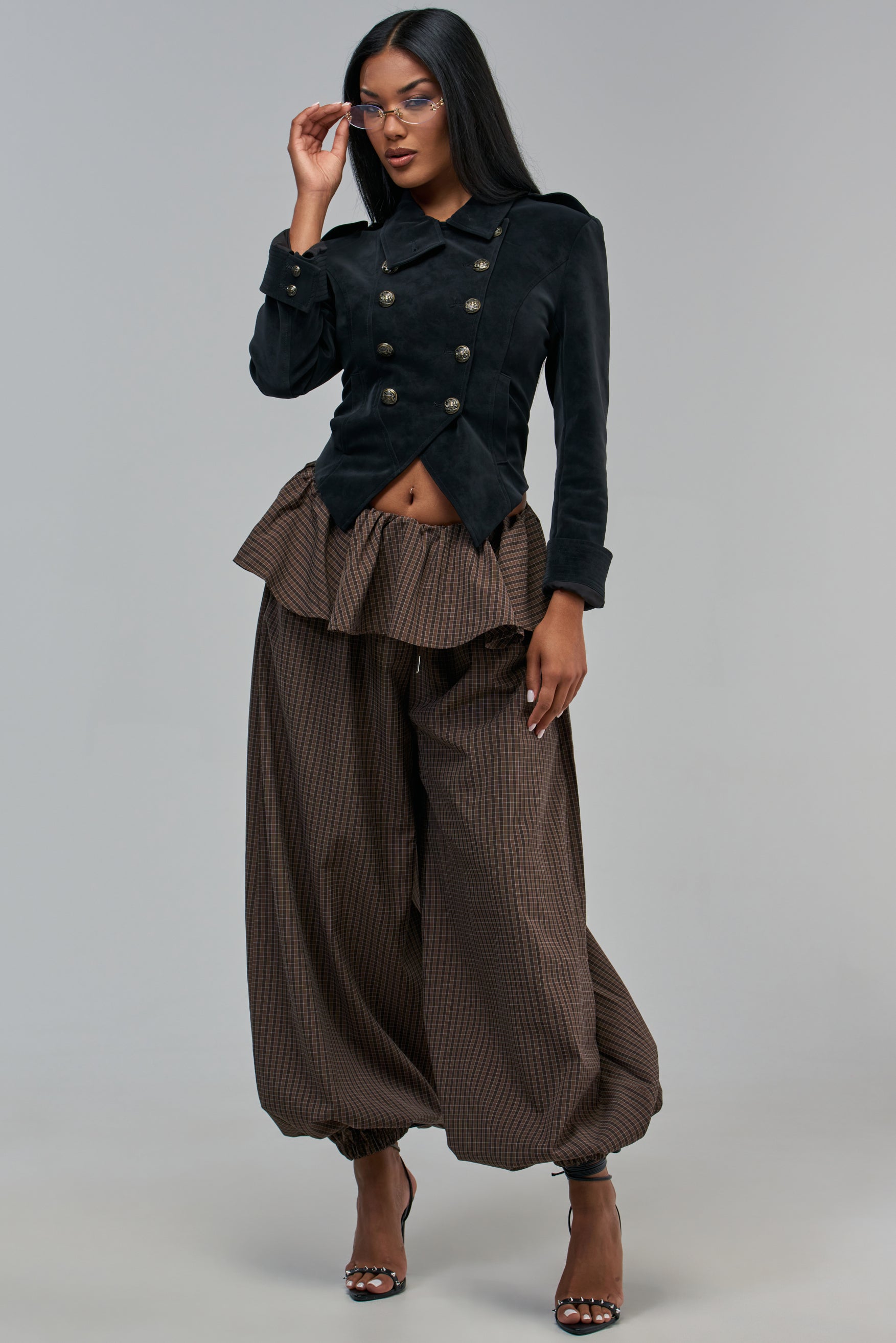 A person wears a dark double-breasted jacket with TRYING SOMETHING DIFF BALLOON PANT WITH SKIRT OVERLAY, featuring brown plaid balloon pants with a skirt overlay in a streetwear style.