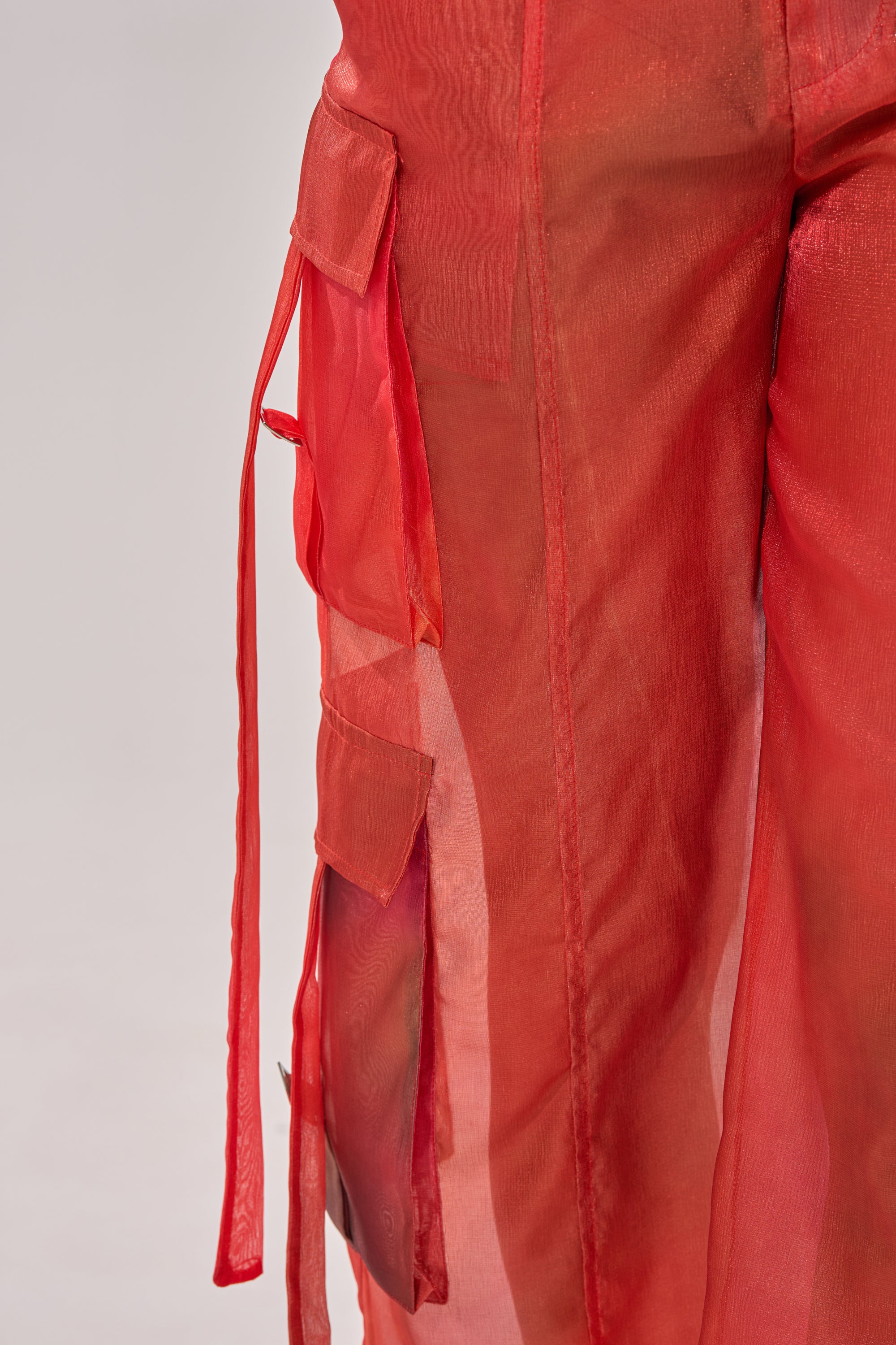 Close-up of the STAINED RED LIGHTWEIGHT CARGO PANT, showcasing a wide-leg silhouette, multiple pockets, and long loose side straps against a neutral background. 7