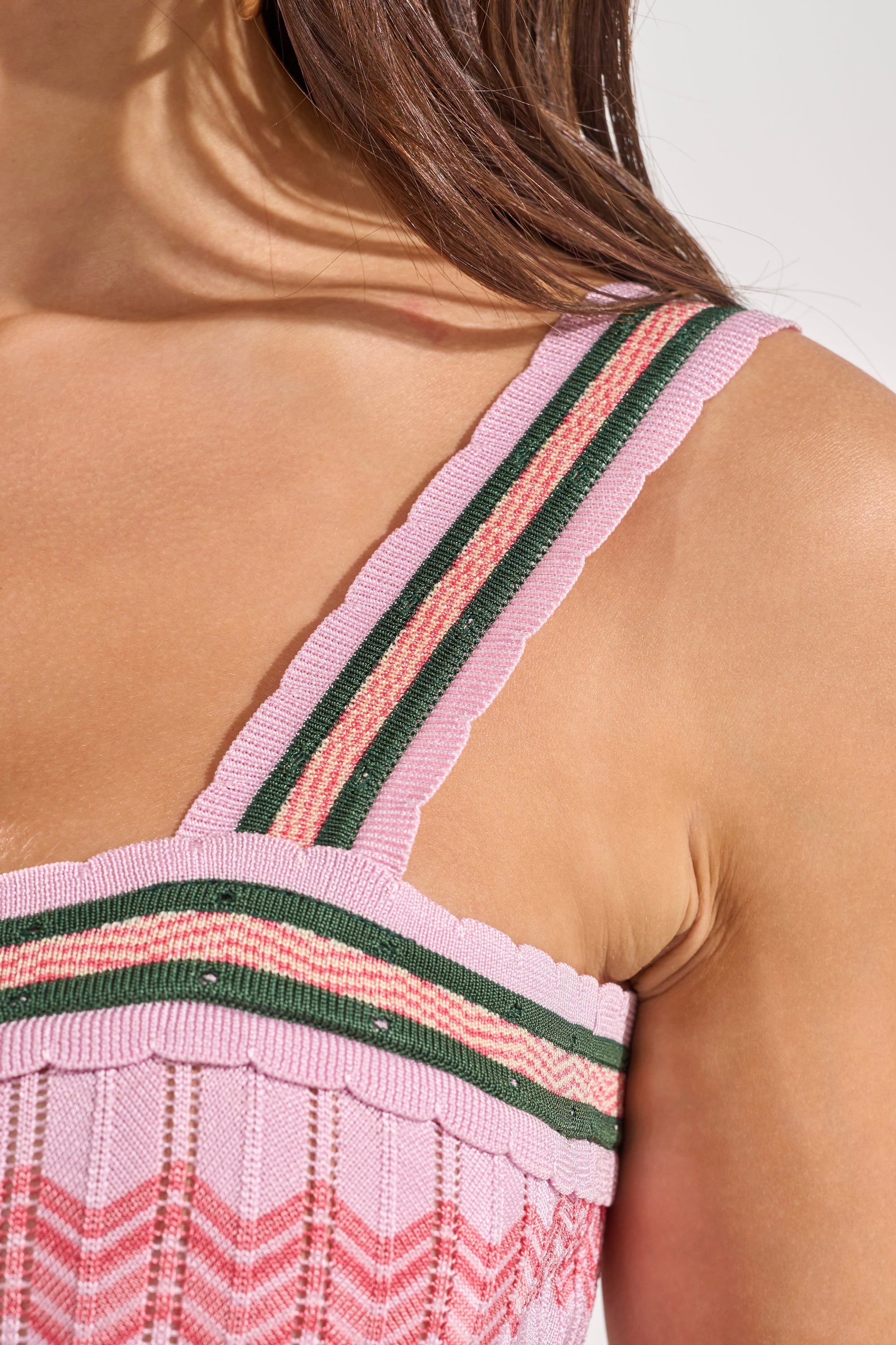 Close-up of a woman’s shoulder and upper chest wearing the HEAT WAVE KNIT MAXI DRESS, a pink chevron maxi with wide pink straps, green and peach stripes, and a textured ribbed pink and red chevron pattern. 4