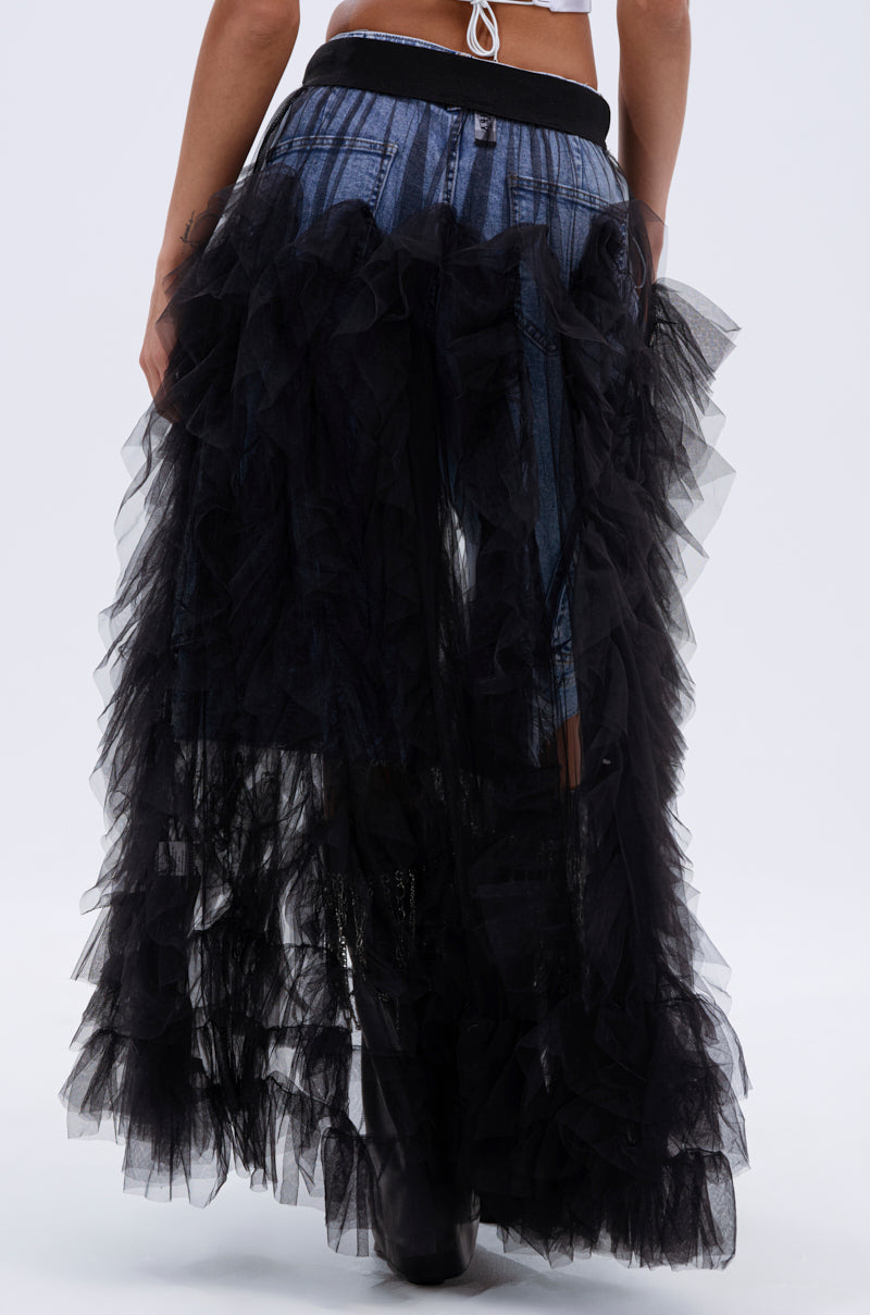 A person models the DRESSED TO IMPRESS MAXI SKIRT—a layered black mesh skirt—over denim pants, shown from the waist down with the back visible against a plain white background.