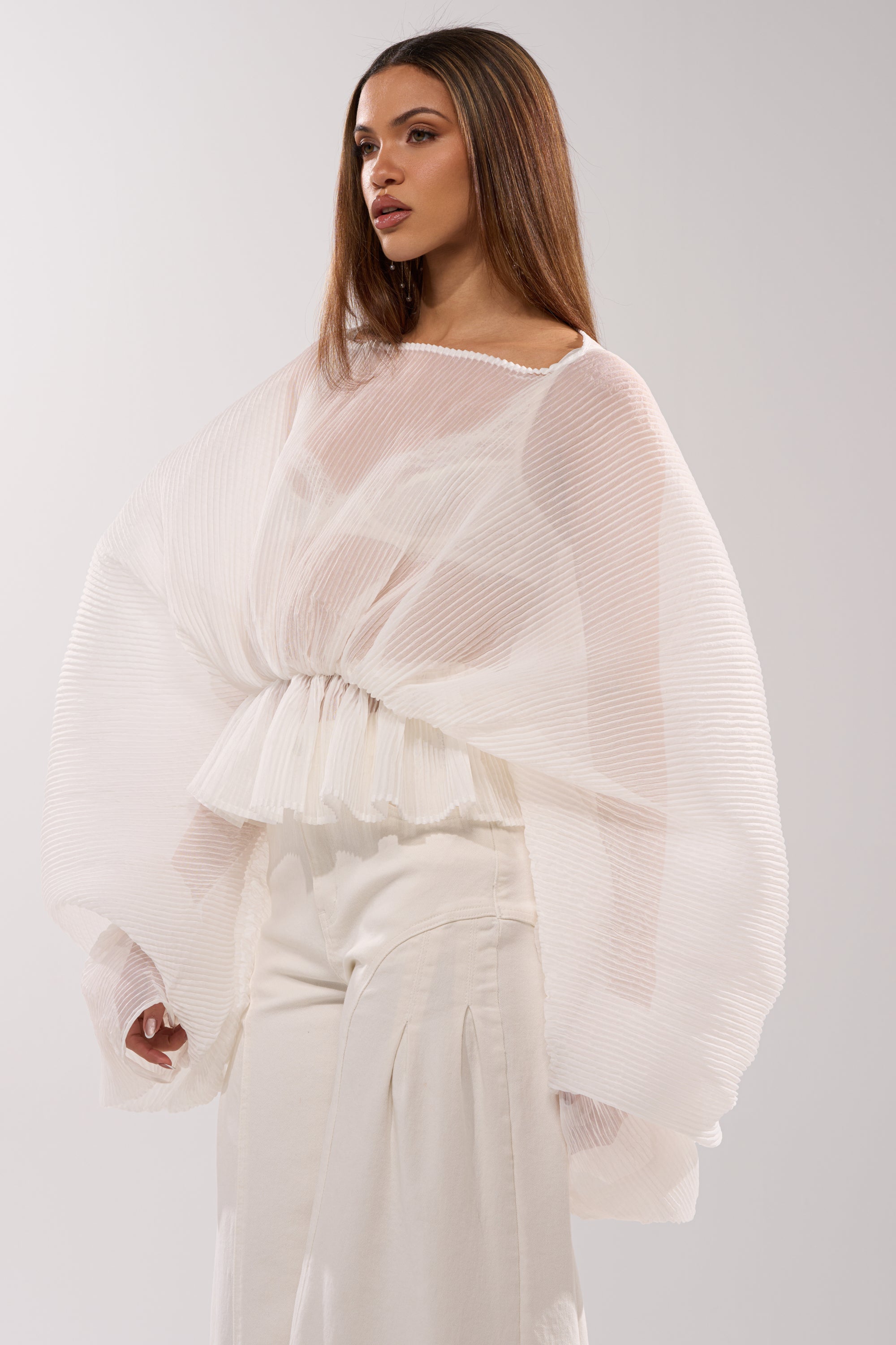 A woman wearing the PRETTY GIRL PROBLEMS BLOUSE IN WHITE, featuring a delicate peplum hem.