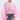 A woman poses confidently in the PRETTY GIRL PROBLEMS BLOUSE—a sheer, light pink pleated top with voluminous batwing sleeves and ruffled details—paired with blue jeans, large hoop earrings, and a blush clutch.