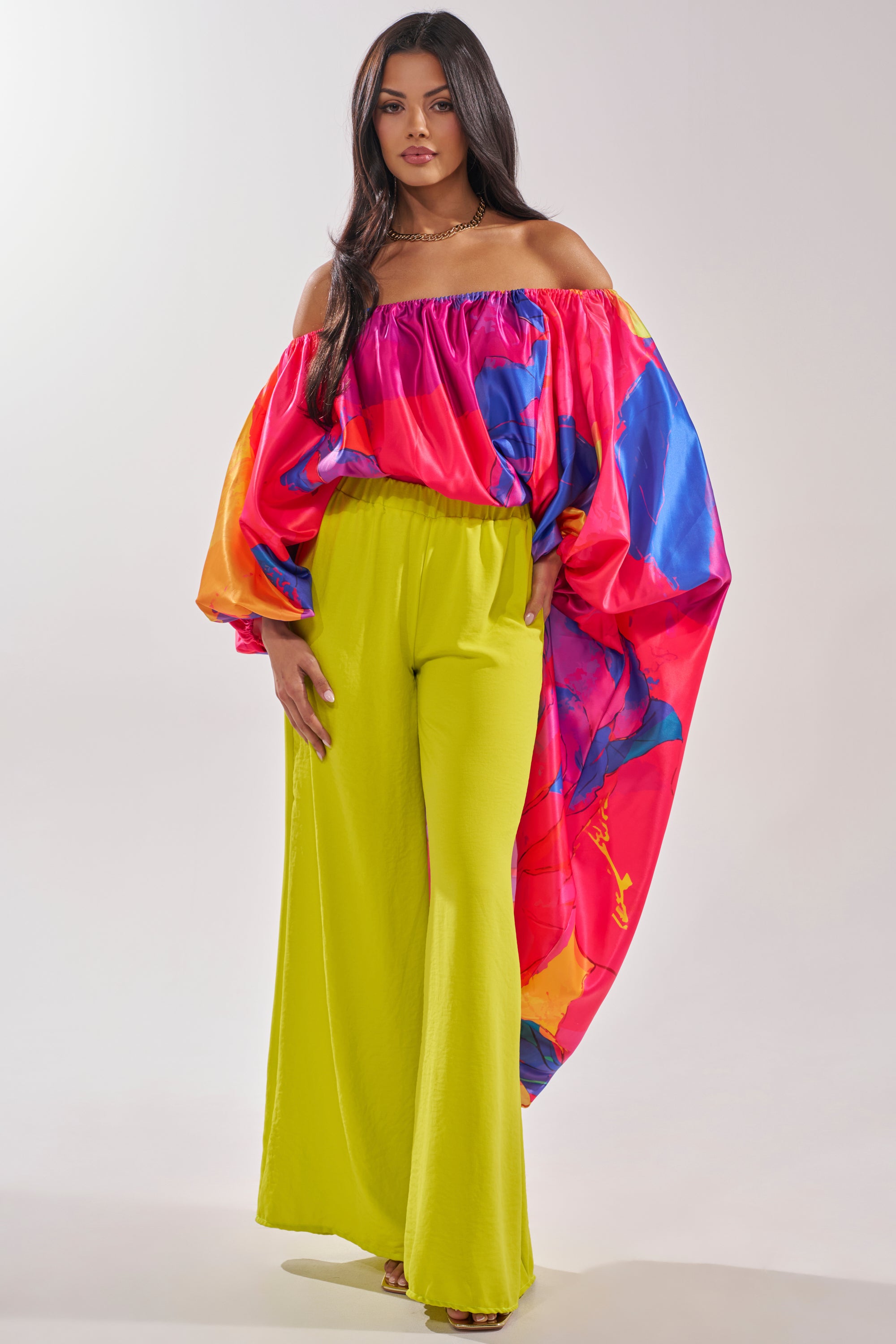 A woman poses in the BE WITH ME BLOUSE, featuring bold, voluminous colorful sleeves—ideal for vacation outfits—styled with high-waisted, wide-leg neon yellow pants and strappy heels against a plain background. 0