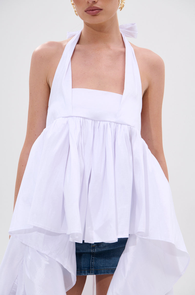A woman models the TOO COOL HIGH LOW TOP—a white, sleeveless halter with a flared, gathered design and neck ties—styled with a blue denim mini skirt against a plain background for a chic look. 7