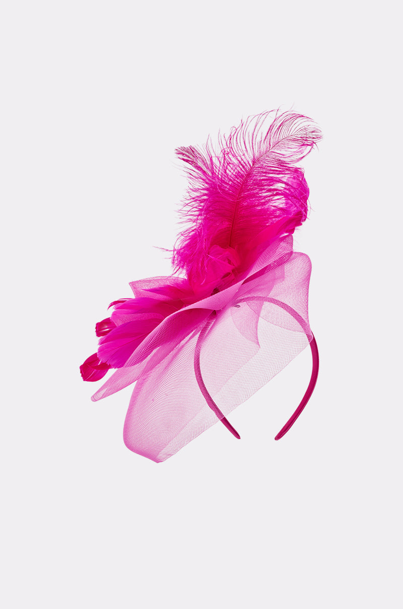 The DERBY DAY PINK FASCINATOR is a bright pink headband with a large translucent mesh bow and vibrant feathers, shown against a plain white background. 4