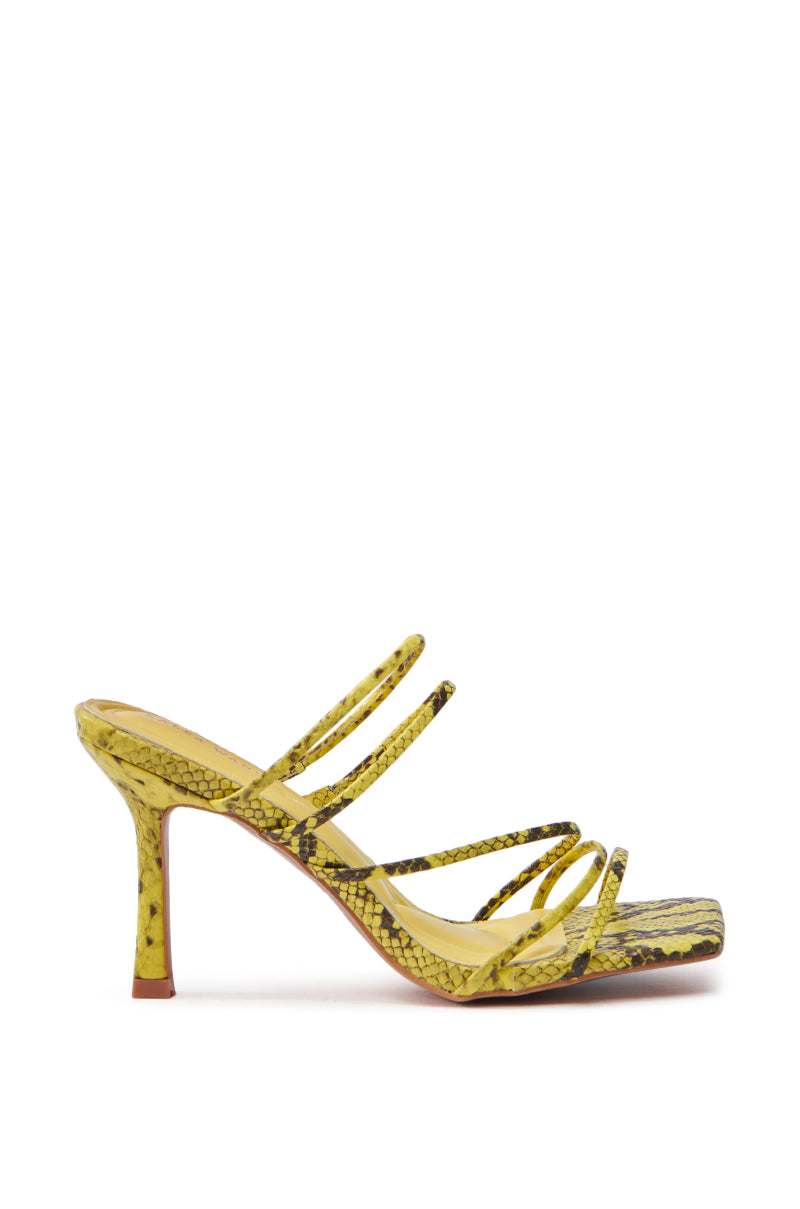 The AZALEA WANG HUGHIE YELLOW SNAKE SANDAL is a high-heeled shoe with multiple thin straps, crafted from vegan leather. It has a yellow snake print, an open square toe, and boasts a sleek, modern design.