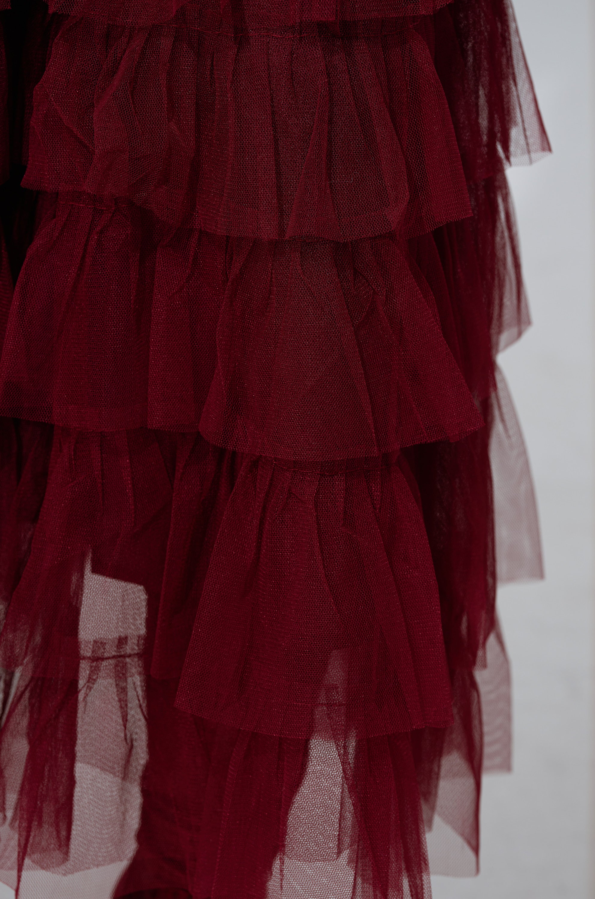 Close-up of the STARS ALIGNED MESH RUFFLE MAXI SKIRT IN BURGUNDY, featuring layered tulle mesh with ruffled tiers for a sheer, lightweight feel and voluminous texture.