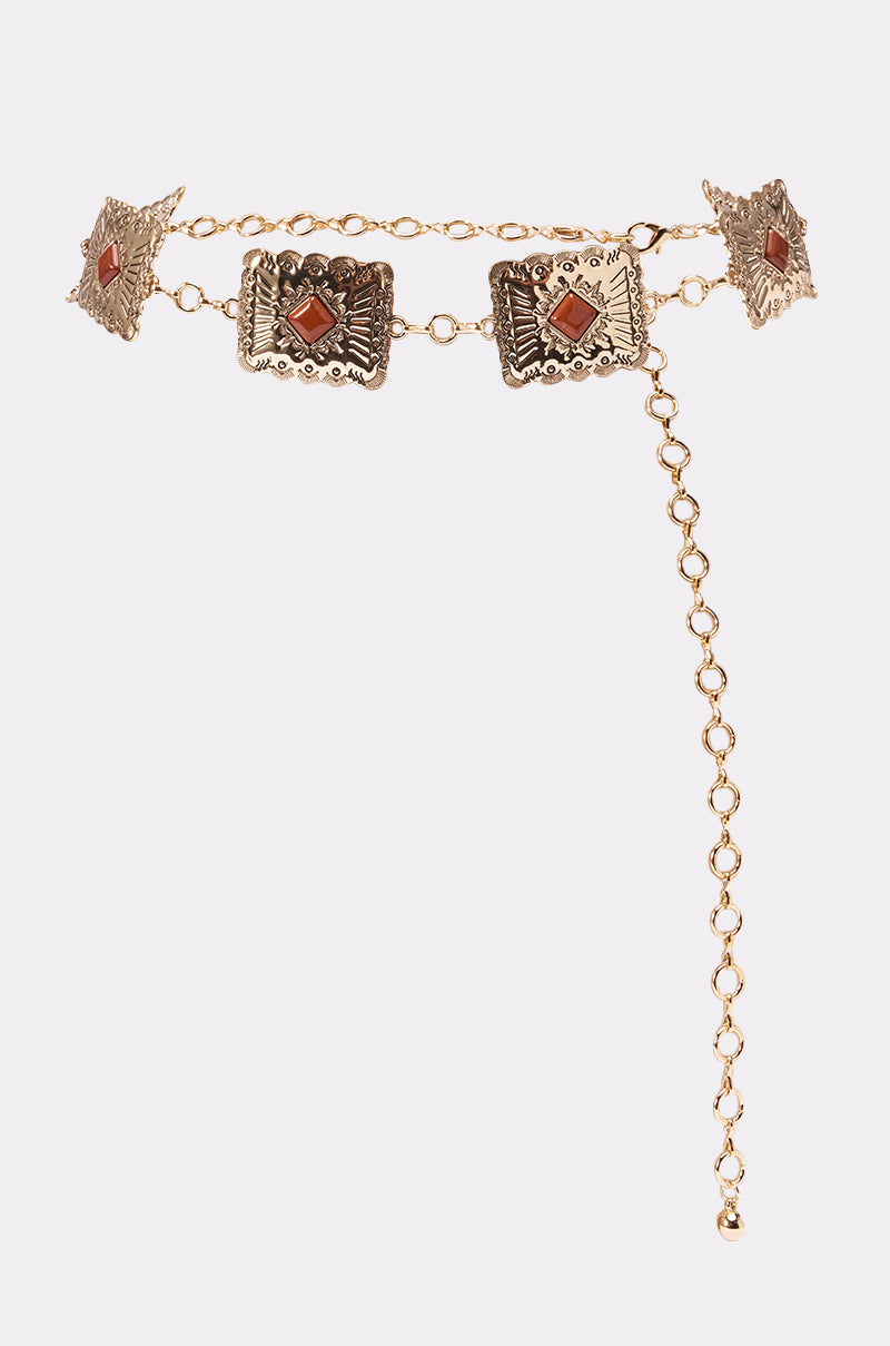 The LOCKED IN LOVE CHAIN BELT features ornate gold medallions with square filigree plates and orange gemstone centers, linked in a boho style. An adjustable dangling chain makes it the perfect striking festival accessory. 1