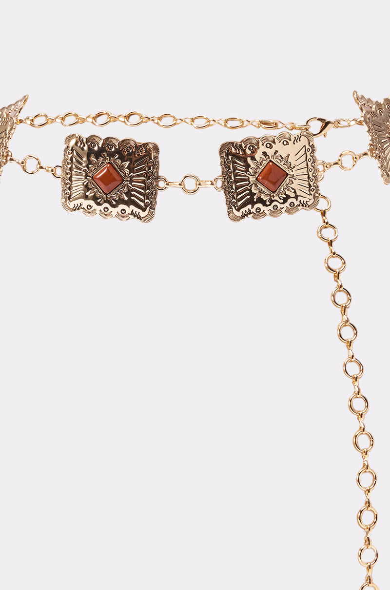 The LOCKED IN LOVE CHAIN BELT features gold rectangular pendants with engraved details and a central red gemstone on each, finished with an adjustable clasp. 2