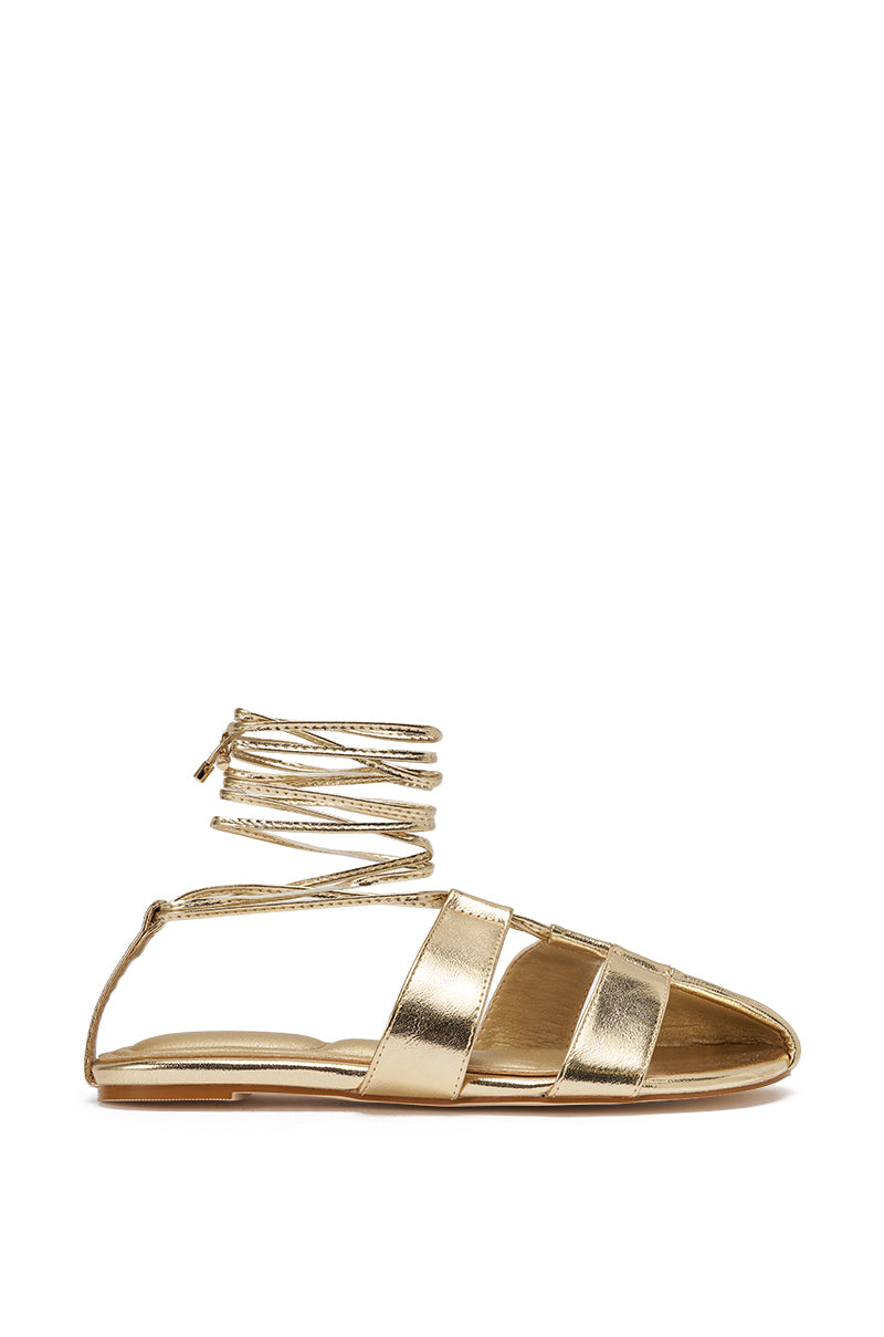 The AZALEA WANG ICHIRO GOLD PEEP TOE FLAT is a gold metallic sandal with three wide foot straps and thin lace-up ankle ties, shown side profile on a white background. It features a comfort cushion insole for added ease. 4