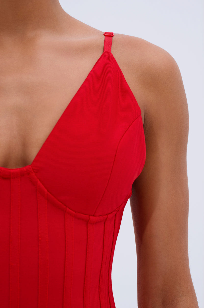 Close-up of a person wearing the FELT CUTE RUFFLE BANDAGE MINI DRESS in red, featuring a sleeveless V-neck design with adjustable straps and seam details. The person's face isn't visible against a plain, light background.