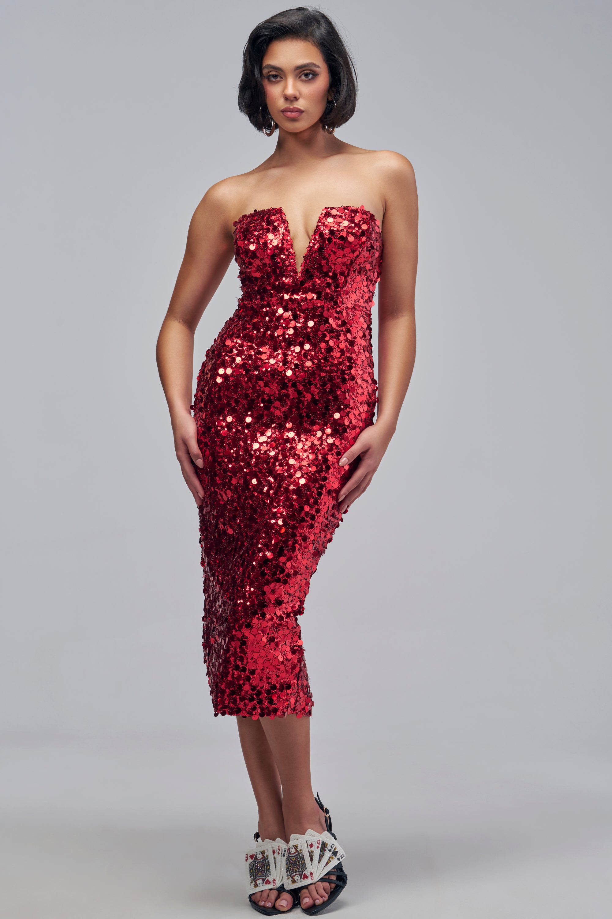 A person wearing a VIP REGULAR SEQUIN MIDI DRESS IN RED, a strapless red sequin midi dress with a deep V-neckline.