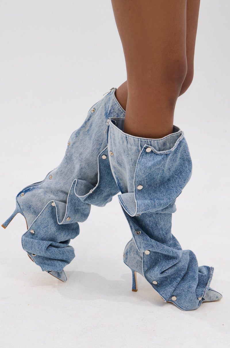 A person wearing the AZALEA WANG IMOGINE DENIM SNAP BOOT—unique, knee-high boots with a pointed toe, stiletto heel, silver snap buttons, and exaggerated gathered denim for a bold statement look.