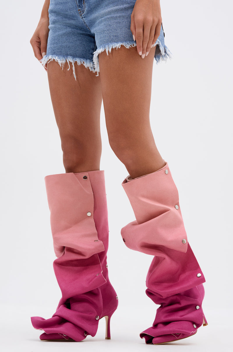 A person wearing frayed denim shorts and loose-fitting, slouchy AZALEA WANG IMOGINE PINK MULTI FAUX SUEDE BOOTS with snap buttons stands against a plain white background.