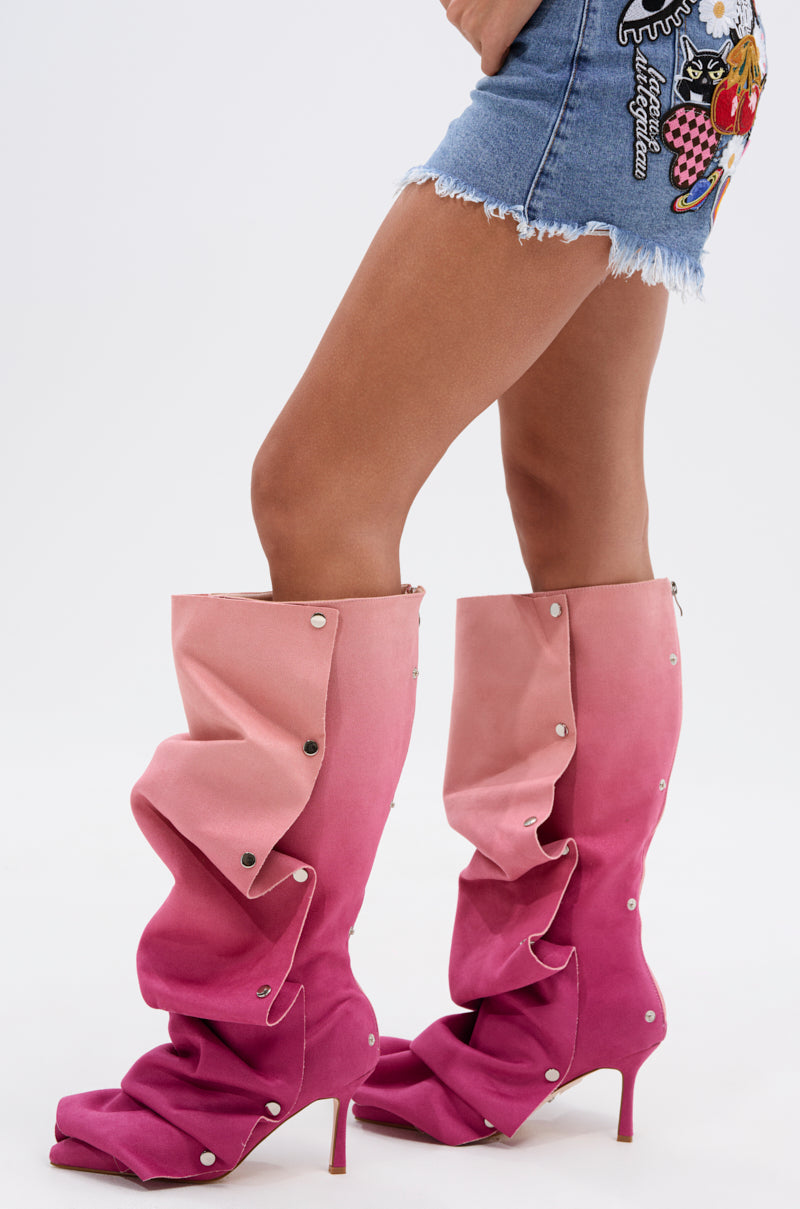 A person in a short embroidered denim skirt wears AZALEA WANG IMOGINE PINK MULTI FAUX SUEDE BOOTS—tall, scrunched, ombré pink stilettos—while standing against a plain white background.
