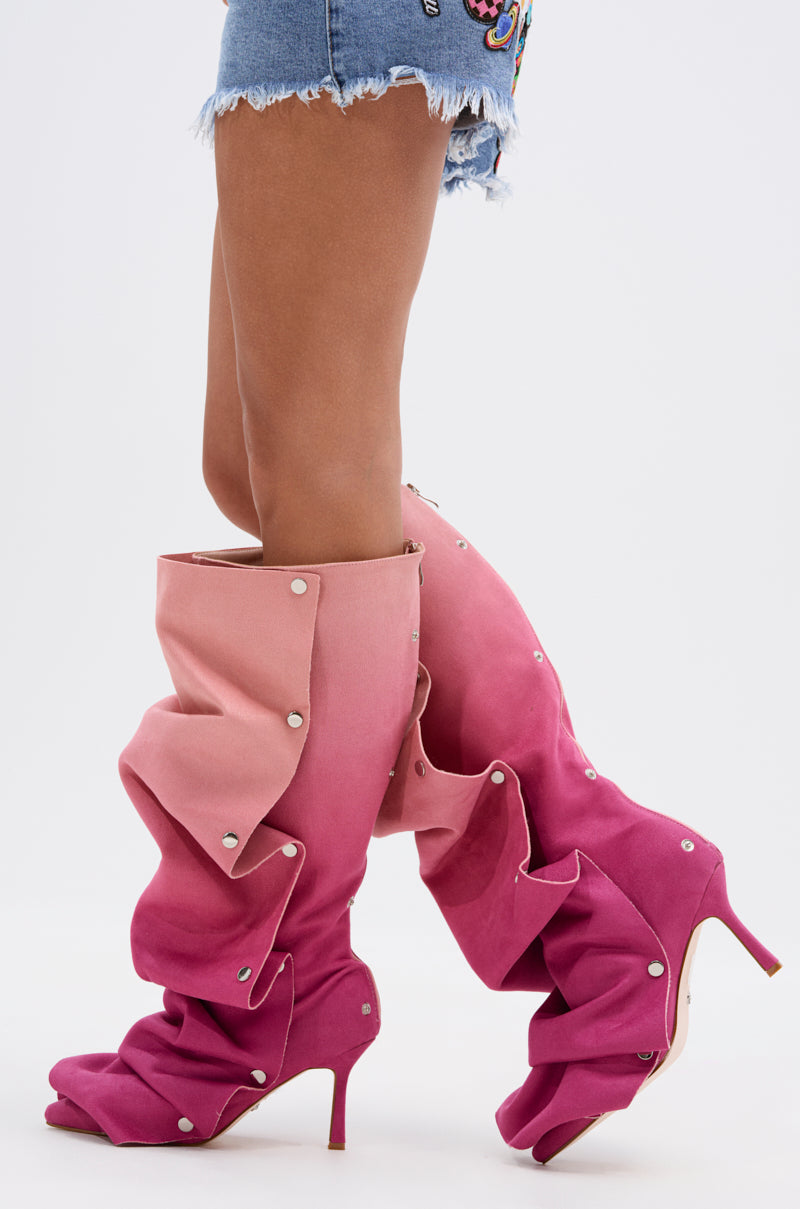 A person wearing frayed denim shorts and AZALEA WANG IMOGINE Pink Multi Faux Suede Boots with knee-high ombré pink, stiletto heels, and silver studs, standing against a white background.