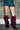 A person wearing a blue denim mini skirt and AZALEA WANG IMOGINE Purple Ombre Folded Detail Stiletto Boots stands before a glass block wall, with only their legs and lower torso visible.